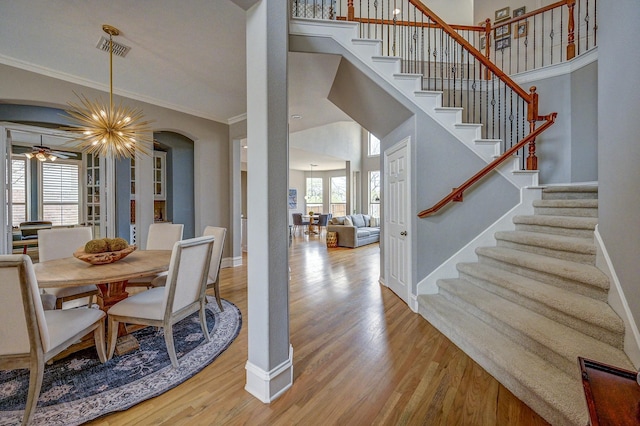 dining area featuring wood finished floors, visible vents, baseboards, arched walkways, and crown molding