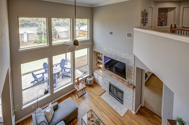 living area with visible vents, light wood-style floors, ornamental molding, and a fireplace