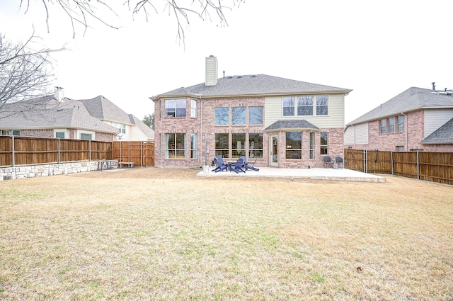 back of property with brick siding, a patio, a chimney, and a fenced backyard