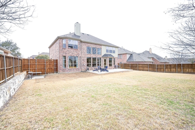 rear view of house featuring a yard, brick siding, a fenced backyard, and a patio area