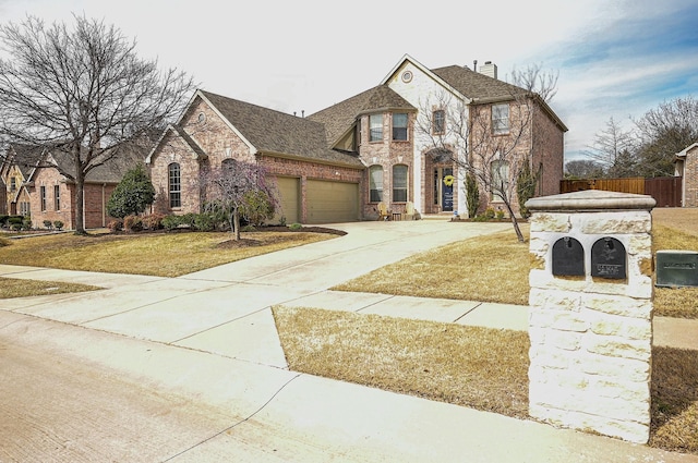 french country style house featuring brick siding, a front lawn, fence, concrete driveway, and stone siding