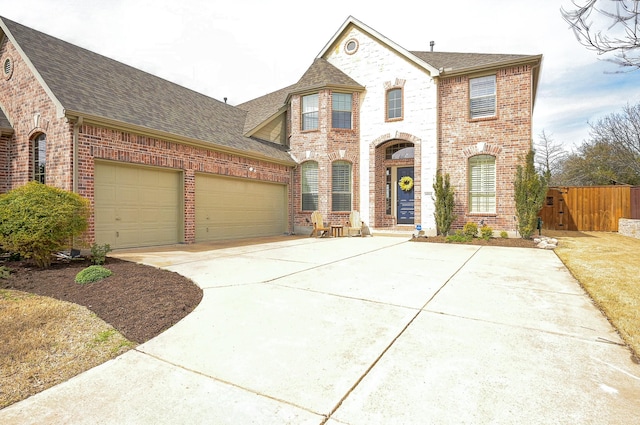 view of front of house with fence, roof with shingles, an attached garage, concrete driveway, and brick siding