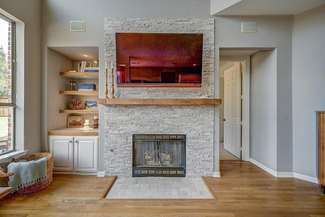 living area featuring built in features, baseboards, plenty of natural light, and wood finished floors