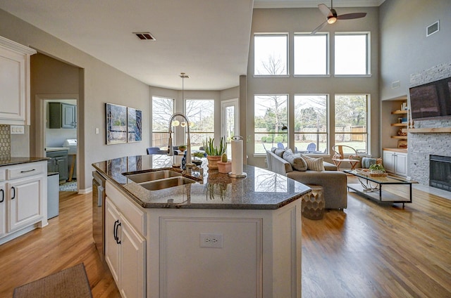 kitchen with a ceiling fan, a fireplace, visible vents, and a sink