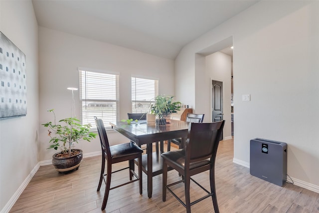 dining area featuring vaulted ceiling, baseboards, and light wood finished floors