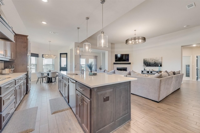 kitchen featuring visible vents, a fireplace, light wood-style floors, and a sink