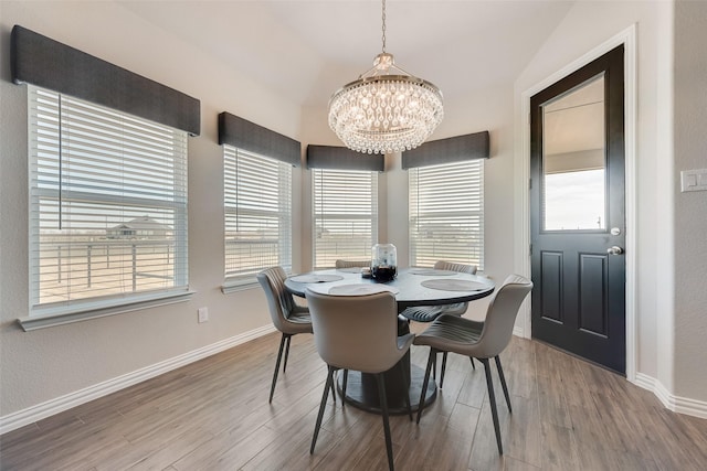 dining area with baseboards, an inviting chandelier, and wood finished floors