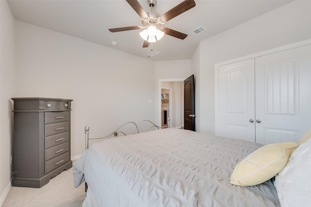 bedroom with a closet, visible vents, light colored carpet, and baseboards