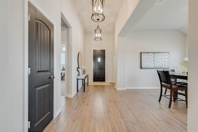 foyer featuring a notable chandelier, light wood-style flooring, and baseboards