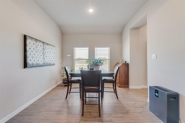 dining area with light wood-type flooring, baseboards, and lofted ceiling