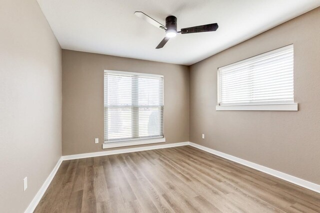 empty room featuring a ceiling fan, wood finished floors, and baseboards