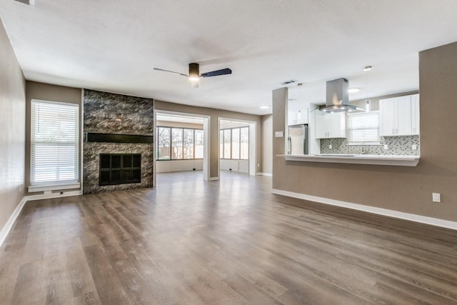 unfurnished living room with dark wood finished floors, ceiling fan, baseboards, and a premium fireplace