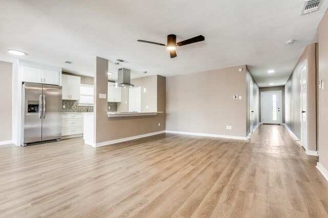 unfurnished living room featuring light wood finished floors, visible vents, baseboards, and a ceiling fan