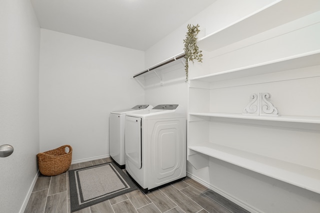 clothes washing area with laundry area, wood tiled floor, baseboards, and washer and clothes dryer