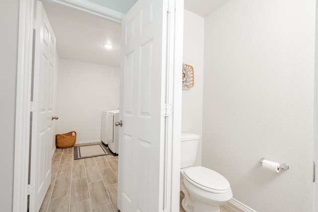 bathroom featuring washer / dryer, toilet, baseboards, and wood tiled floor