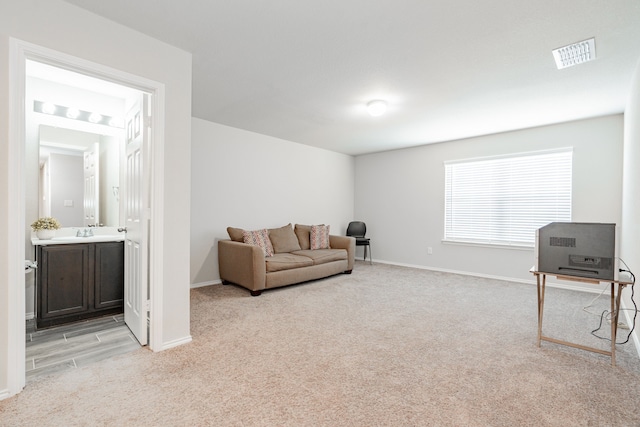 sitting room featuring visible vents, light carpet, and baseboards