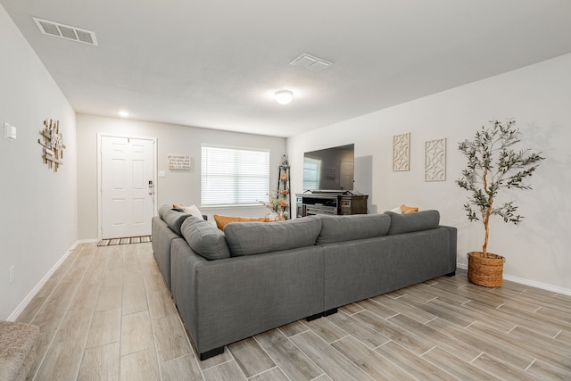 living room featuring visible vents, baseboards, and wood finish floors