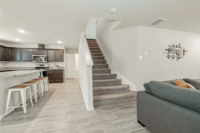 stairway with recessed lighting, visible vents, and wood tiled floor