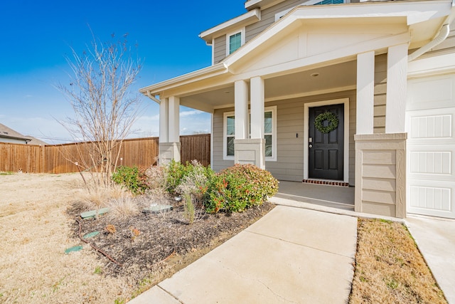 doorway to property with covered porch and fence