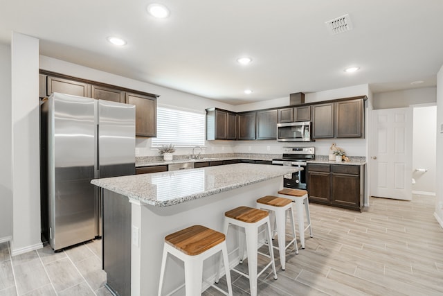 kitchen featuring dark brown cabinetry, visible vents, appliances with stainless steel finishes, and a kitchen island