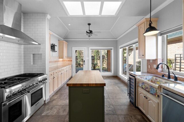 kitchen featuring wood counters, a center island, stainless steel appliances, wall chimney range hood, and lofted ceiling