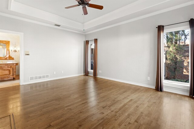 unfurnished room with visible vents, a raised ceiling, and wood finished floors