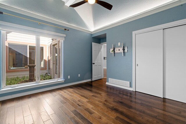 unfurnished bedroom with visible vents, a textured ceiling, wood finished floors, and vaulted ceiling