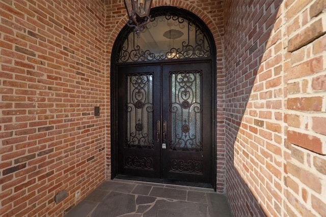 doorway to property featuring brick siding and french doors