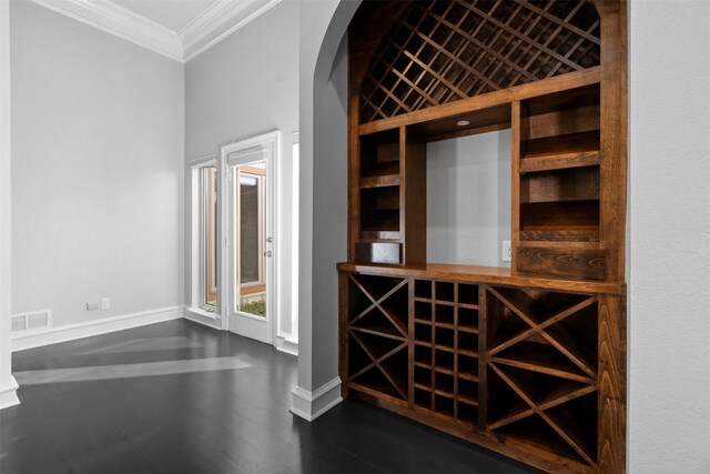 wine area with visible vents, baseboards, ornamental molding, arched walkways, and dark wood-style flooring