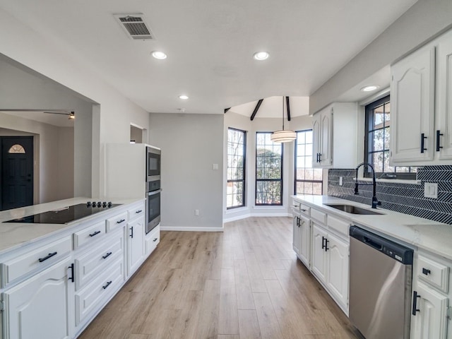 kitchen with visible vents, backsplash, light wood-type flooring, stainless steel appliances, and a sink