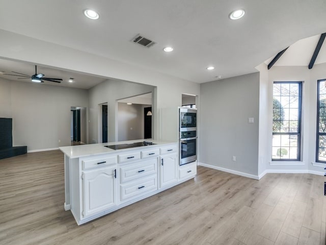 kitchen with visible vents, stainless steel appliances, light countertops, white cabinetry, and open floor plan