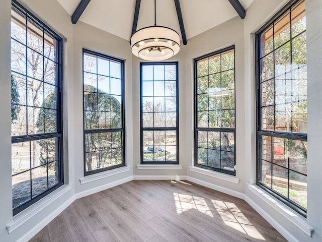 interior space with lofted ceiling with beams, a wealth of natural light, and a chandelier