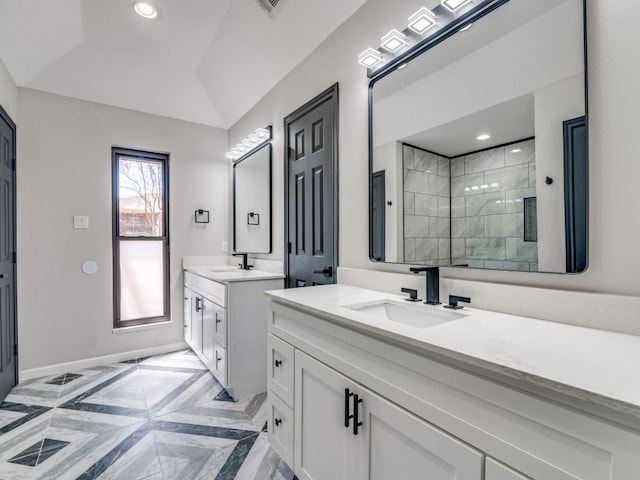 bathroom featuring two vanities, tiled shower, recessed lighting, and a sink