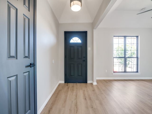 foyer featuring light wood finished floors, baseboards, and lofted ceiling