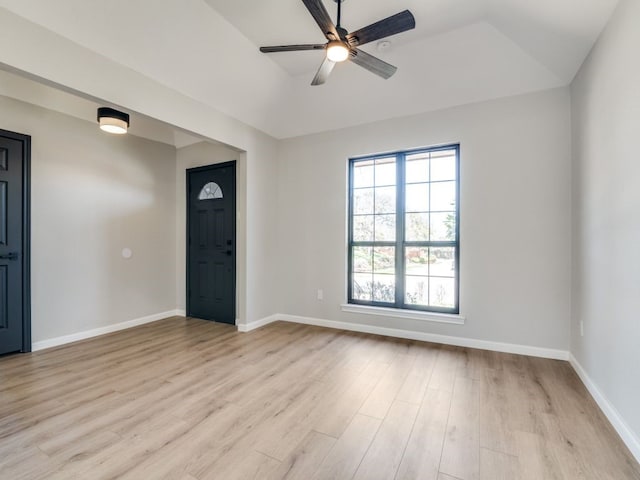 spare room featuring a raised ceiling, baseboards, light wood finished floors, and ceiling fan