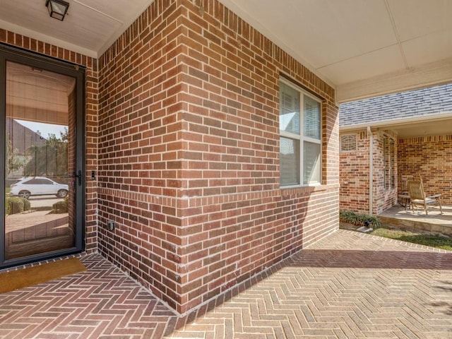 entrance to property with brick siding and roof with shingles