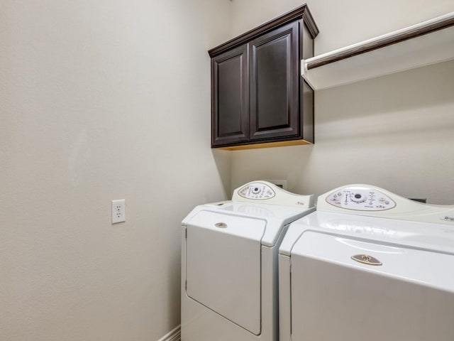 clothes washing area with cabinet space and separate washer and dryer