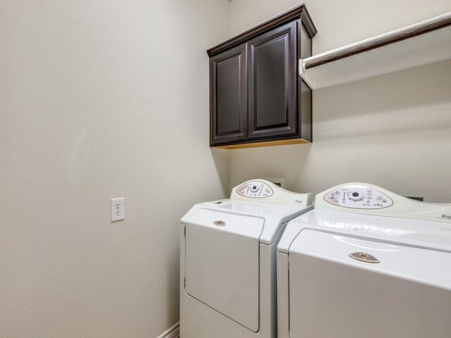 clothes washing area with cabinet space and separate washer and dryer