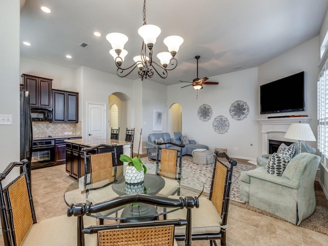 dining space featuring visible vents, recessed lighting, a fireplace, arched walkways, and ceiling fan with notable chandelier