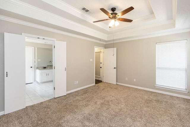 spare room with visible vents, light carpet, a tray ceiling, crown molding, and ceiling fan