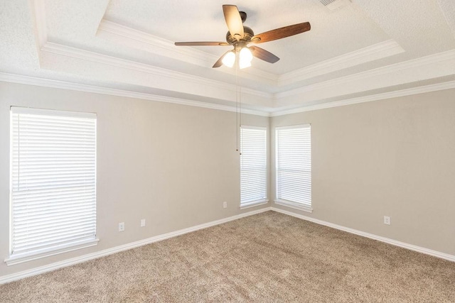 carpeted empty room featuring baseboards, a tray ceiling, ornamental molding, a textured ceiling, and a ceiling fan