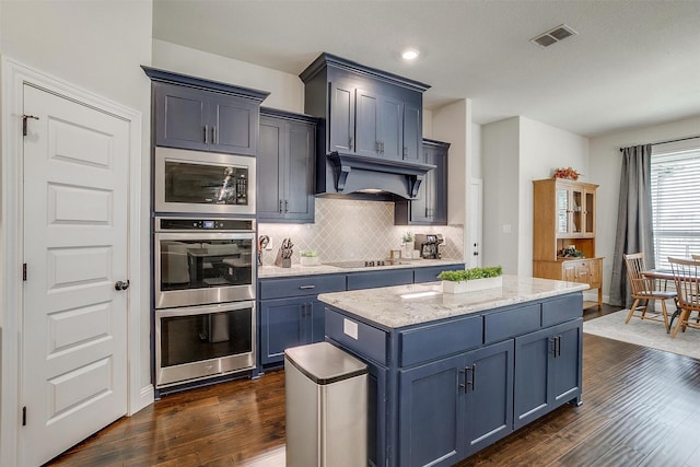 kitchen with custom range hood, a kitchen island, tasteful backsplash, stainless steel appliances, and dark wood-style flooring