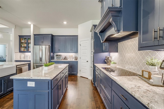 kitchen featuring dark wood finished floors, custom range hood, light stone countertops, and stainless steel appliances