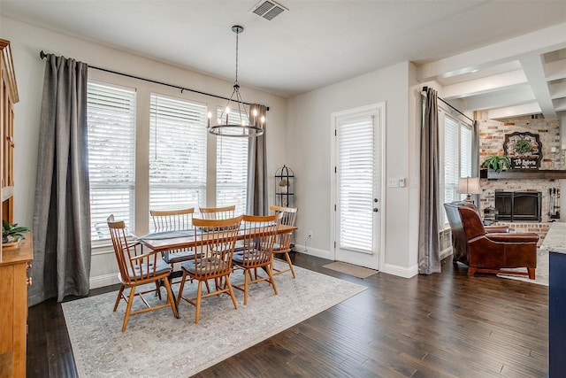 dining area with visible vents, baseboards, dark wood-style flooring, a brick fireplace, and a notable chandelier