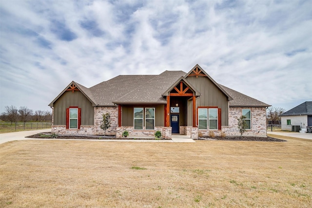 view of front of property featuring board and batten siding, fence, a front lawn, and roof with shingles