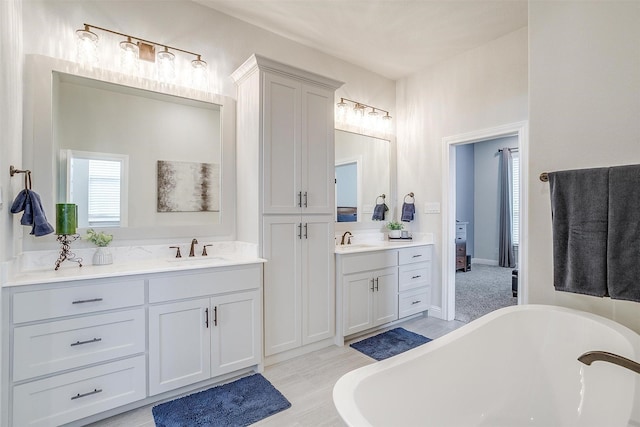 bathroom featuring a freestanding tub, two vanities, and a sink