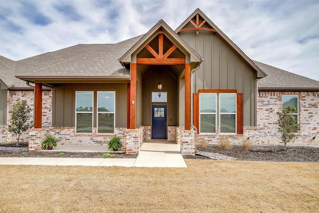 view of front of house featuring brick siding, board and batten siding, and a shingled roof