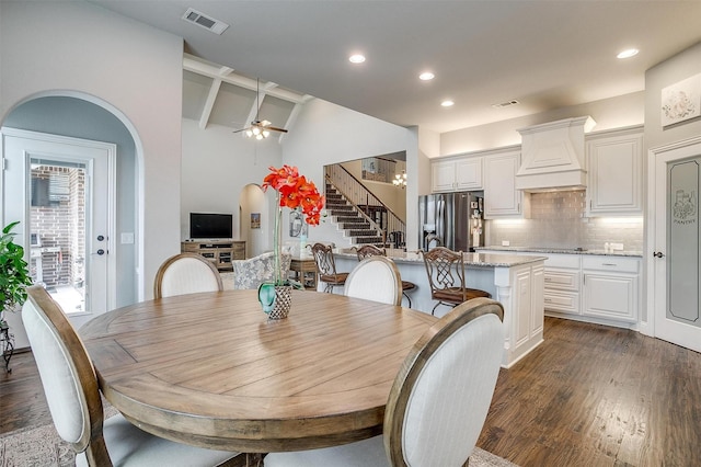 dining room featuring arched walkways, visible vents, stairway, and dark wood-type flooring