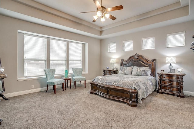 bedroom with a tray ceiling, baseboards, carpet floors, and a ceiling fan