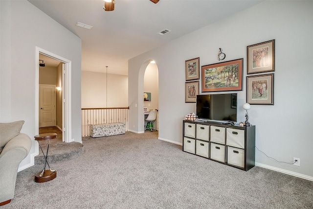 sitting room with arched walkways, visible vents, carpet floors, and baseboards